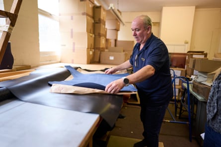 Gary Billingham, factory manager at Ettinger, examines navy leather pieces on a workbench
