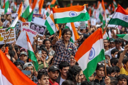 People wave Indian national flags in a large crowd