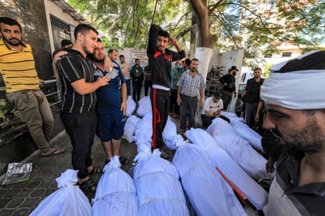 People gather by the wrapped bodies of victims who died in an overnight blast at the hospital. The death toll has been put variously between 300 and 500.