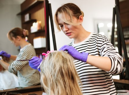 Person experiencing a hair colour transformation from a hairdresser, seated in a styling chair