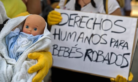 Demonstrators hold a baby doll and placard reading ‘Human rights for stolen babies’ outside a court in Madrid’.