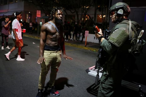 A man talks to a police officer as revelers enjoy spring break festivities despite an 8pm curfew in Miami Beach, Florida.