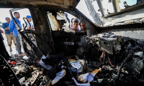 People inspect the burnt out car where World Central Kitchen workers were killed in Deir al-Balah, Gaza
