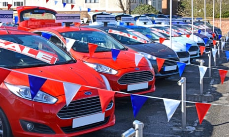 Sale posters on car windscreens surrounded by red, white and blue bunting