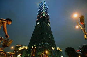 In Taipei, a man rides next to the 101 building lit up with the colours of the French flag in honour of the victims.