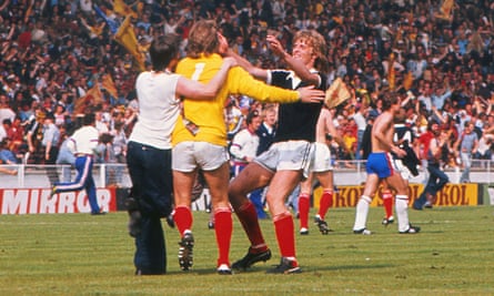 A Scotland fan celebrates on the pitch with Alan Rough and Gordon McQueen at Wembley in 1977
