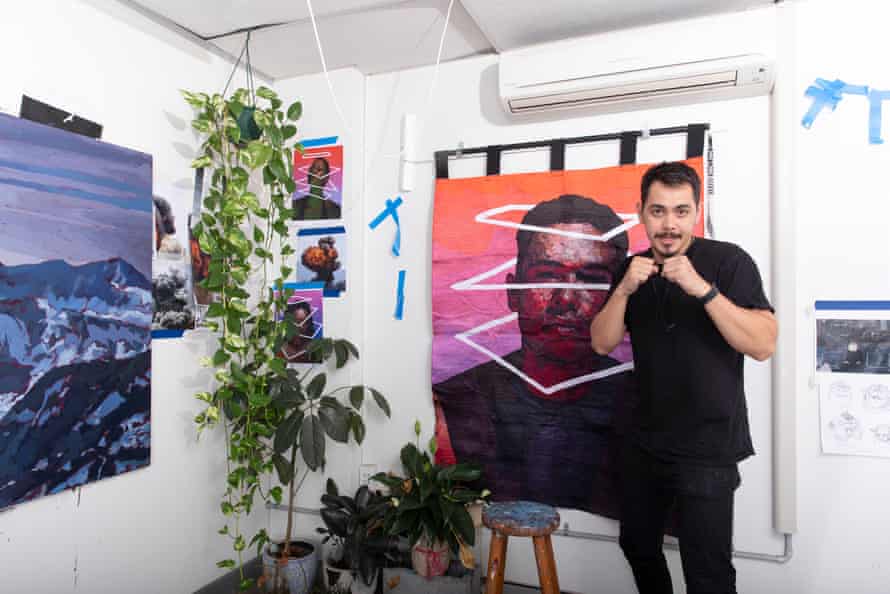 Abdullah in boxing stance in front of his paintings