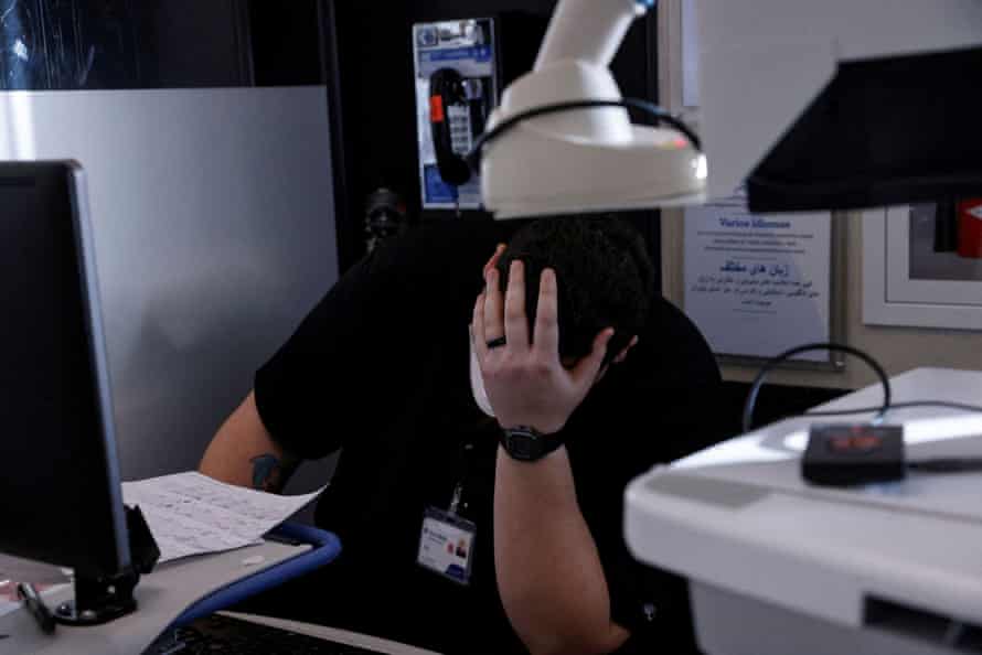A healthcare worker puts her head into her hand while working at a computer in the emergency department.