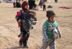A girl carries another child as they flee fighting between Syrian Democratic Forces and Islamic State militants in Baghuz, Syria
