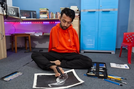 Bikram Bhattarai uses his toes to hold a pen to draw a picture.