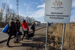 People walk with their belongings at the Astely-Beregsurány border crossing as they flee Ukraine