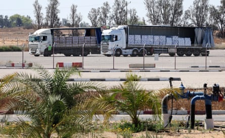 Two trucks parked behind a wire fence