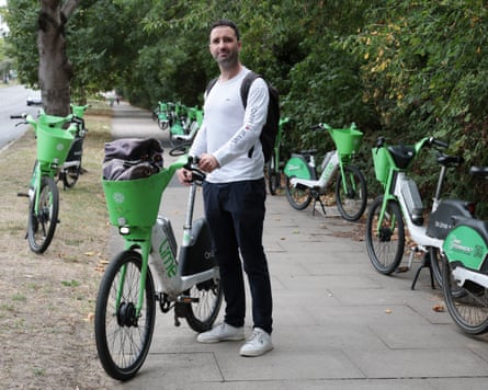 Thomas Letch holding up a Lime bike with several other bikes parked nearby
