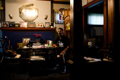 Man sits at table surrounded by belongings at home