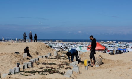 People visit makeshift graves near a refugee camp