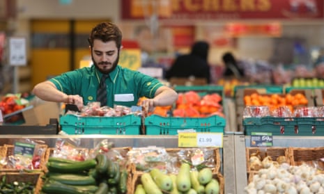 An employee works on the fresh vegetable display at a supermarket.