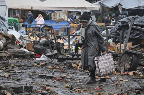 People walk across debris of a fire-damaged market in the morning.