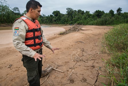 A man in a lifejacket gestures towards dry ground in a park