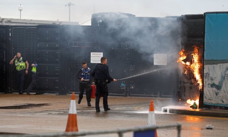 Members of the military and UK Border Force extinguishing a fire from a petrol bomb.