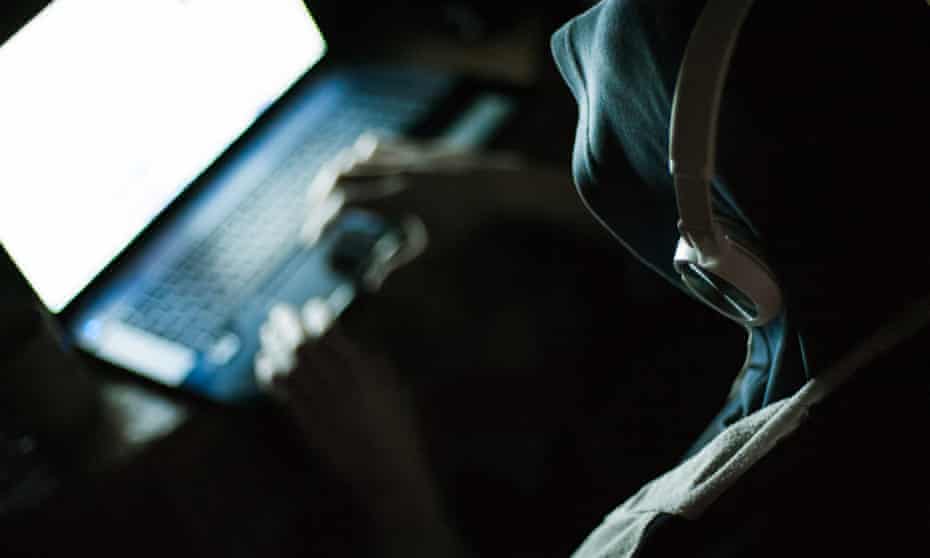Computer hacker working on laptop in the dark