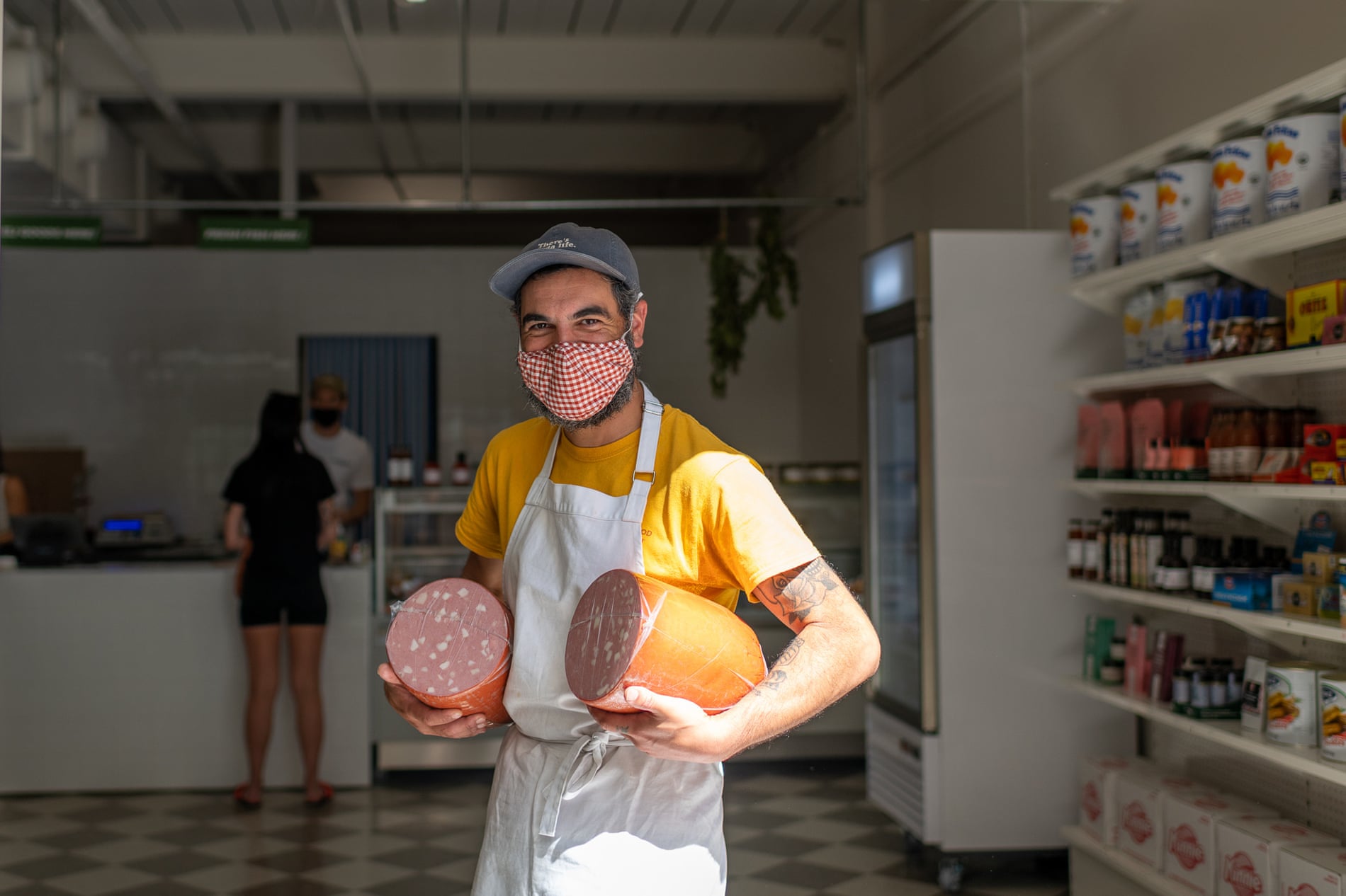 Jake Cassar at his store Mortadeli in Torquay, Victoria holding a large salami under each arm
