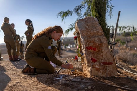 A female soldier places a flower at a memorial site.