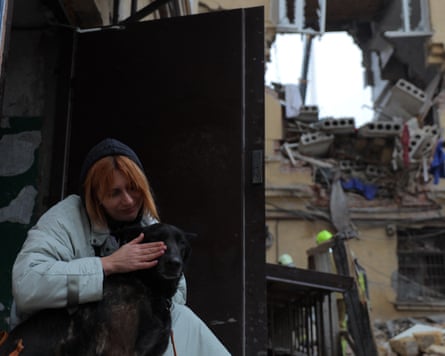 A woman strokes her dog in her severely damaged flat