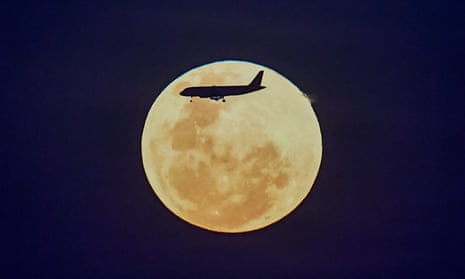 Silhouette of plane flying with yellow moon in background