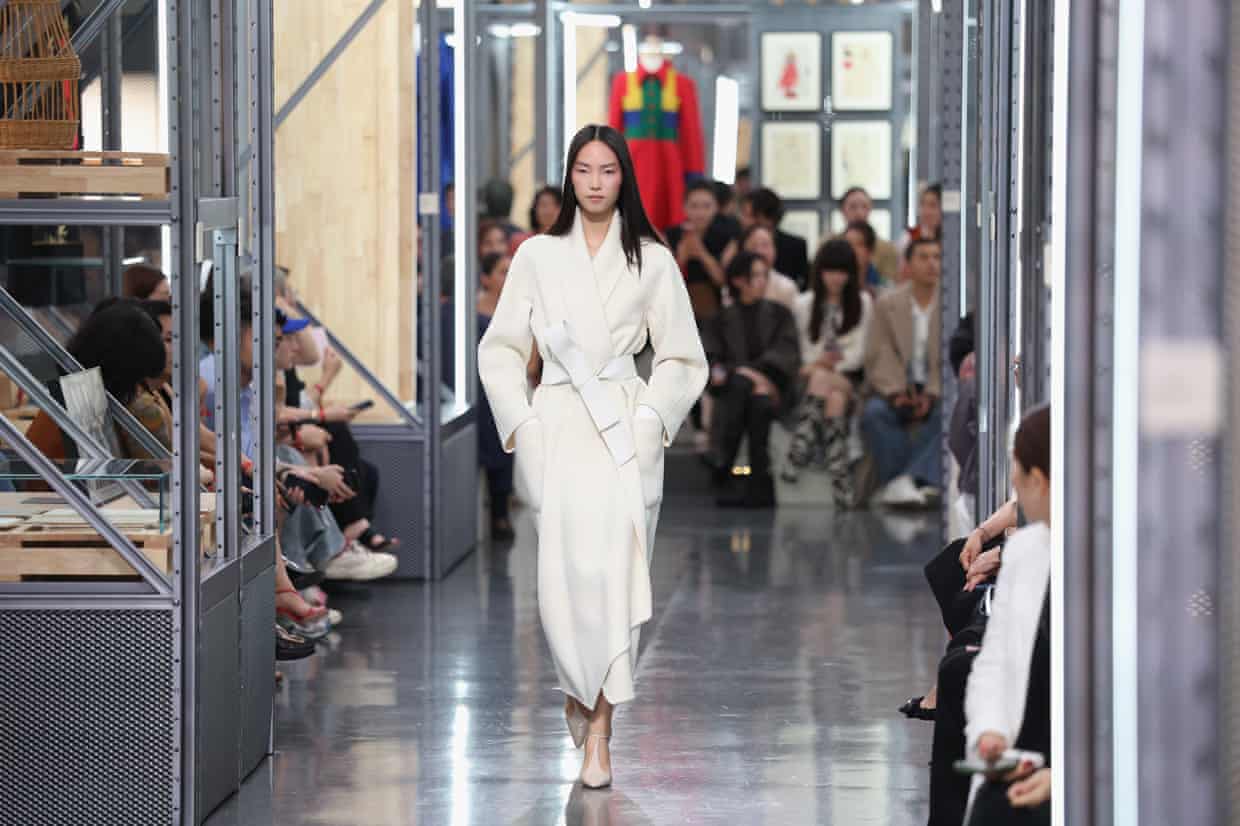 A model in a long coat walks the runway