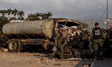 Members of the Venezuelan national guard next to a burnt truck on the border with Colombia