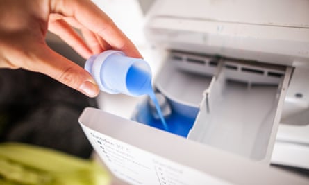 Person pouring laundry liquid into washing machine
