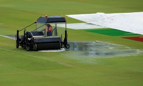 A cricket blotter works through a large puddle on the outfield. 