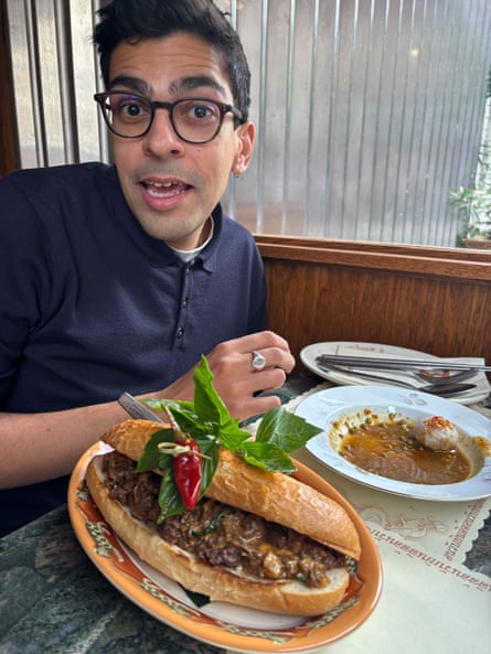 He sits at a diner table with a massive cheese sandwich