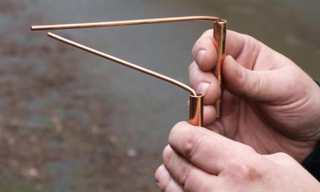 A water engineer uses copper divining rods to trace the course of an underground pipe (UK), a practice known as dowsingEHF85T A water engineer uses copper divining rods to trace the course of an underground pipe (UK), a practice known as dowsing