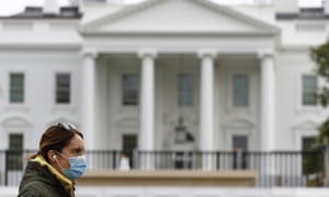 A woman wearing a face mask walks past the White House in Washington on 1 April 2020.