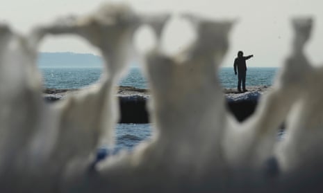 A man is framed by melting ice formed along the railings of the north pier along Lake Michigan  in St Joseph, Michigan, this month.