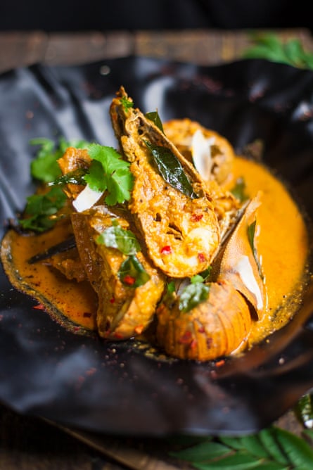 Balmain bug curry garnished with coriander leaves on a black serving plate