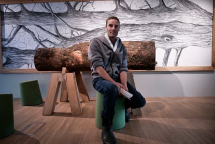 Charlie Whinney sitting by a section of the trunk displayed in a visitor centre.