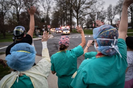 Hospital workers wave as first responders pass by in a caravan of sirens and lights in Valhalla, New York.