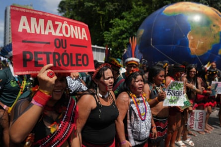 Indigenous activists protest, with a giant globe in backdrop.