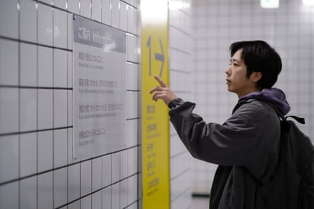 A man points at a sign on a subway wall.