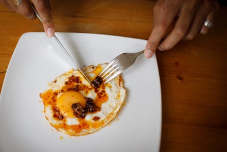 Closeup of Ammar Kalia’s hands cutting up a fried egg with chilli crisp on top