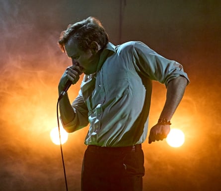Jack Holden speaking into a microphone illuminated by spotlights in Kenrex