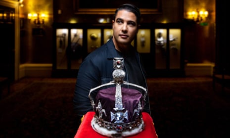 Marc Fennell stands behind a crown set with an enormous round diamond that sits on a pedestal in a darkened room