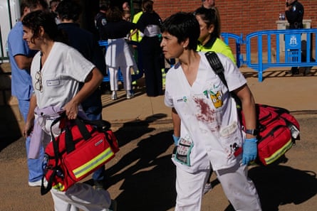 Medical staff, their white uniforms splattered with blood, carry equipment to a makeshift emergency treatment centre,