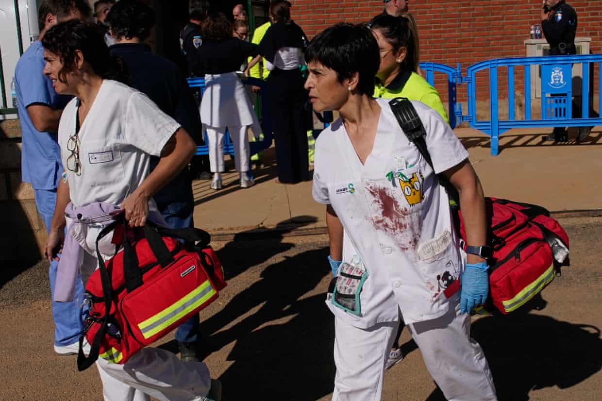 Medical staff, their white uniforms splattered with blood, carry equipment to a makeshift emergency treatment centre,