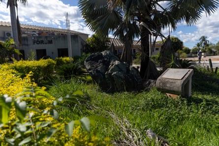 A large black rock in a grassy yard outside a building