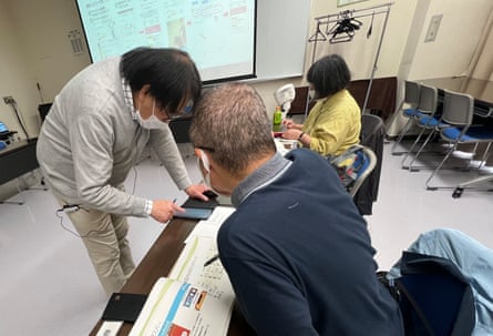 Yasushi Nishioka shows a student how to use his phone