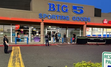 Police offers at a crime scene in front of Big 5, a sporting goods store in a strip mall