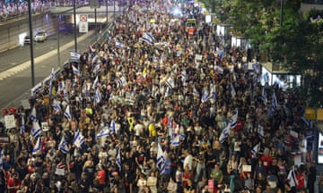 A large crowd of people hold Israeli flags and signs about the hostages in Tel Aviv